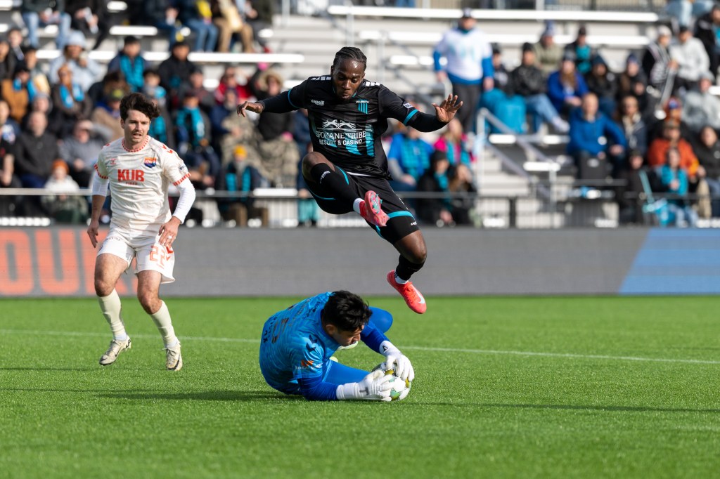 Shavon John-Brown leaps over One Knox goalkeeper
