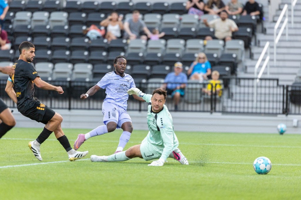 Shavon John-Brown shoots a soccer ball past a goalkeeper
