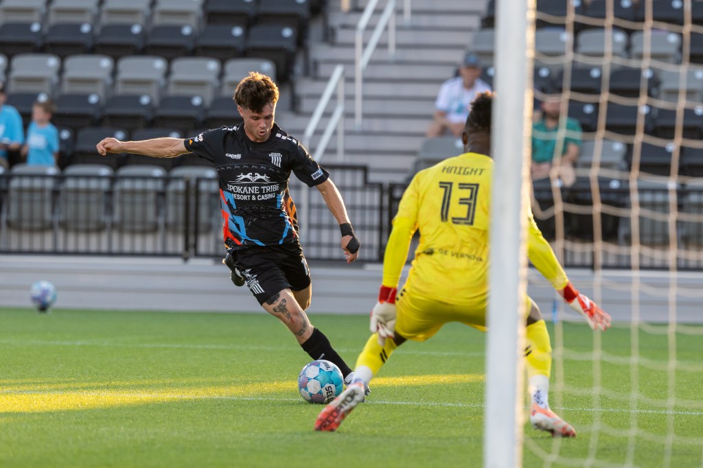 Pictured from partially behind the goal, Jack Denton dribbles toward a goalkeeper who wears a yellow kit